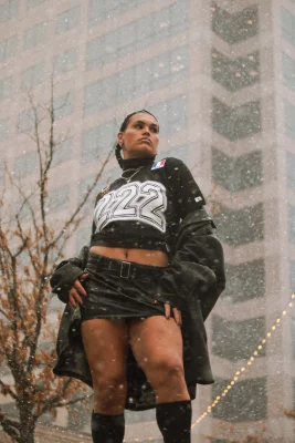 Jaemen Cobb poses in a black mini skirt with a skyscraper behind her.