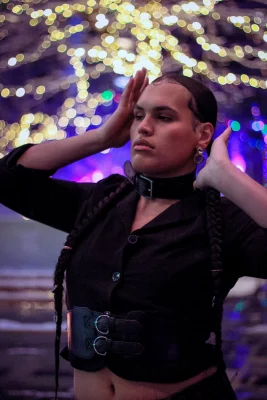 Jaemen Cobb poses in a black outfit with bright lights behind her.