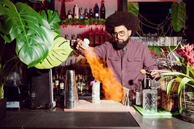 Sam Miller makes a drink at a tiki bar.