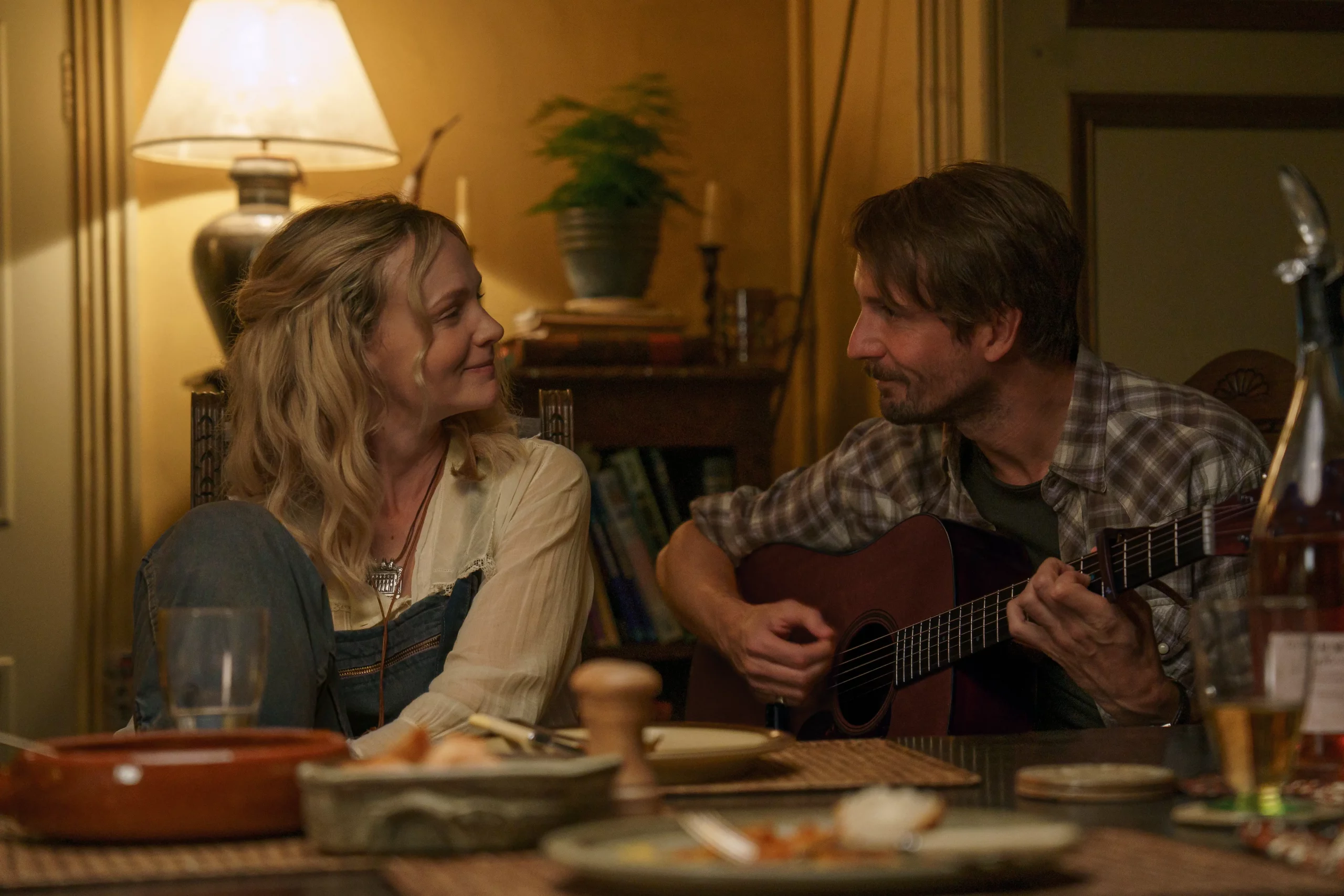 Carey Mulligan sitting next to Tom Basden playinig guitar in The Ballad of Wallis Island.