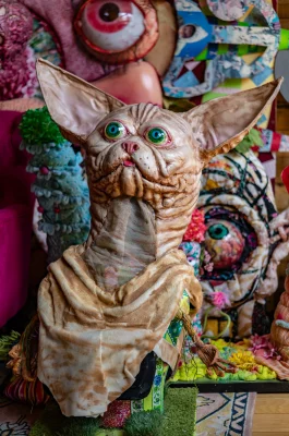 An intricately detailed hairless cat mask sits gazing past the camera