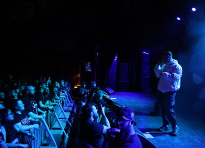 Kneecap on stage in a swath of blue lights and with a packed audience at The Depot in Salt Lake City. Photo: Logan Sorenson.