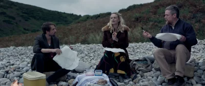Tom Basden, Carey Mulligan and Tim Key on a pebble beach in the Ballad of Wallis Island.