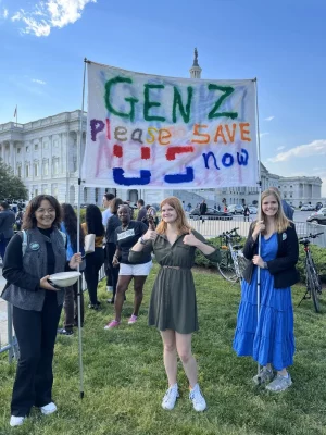 Three student demonstrators holding up a sign at a rally.