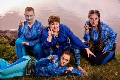 Theatre actors dressed in all-blue by a river.