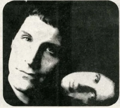 A woman and a man sit next to one another in a black background.